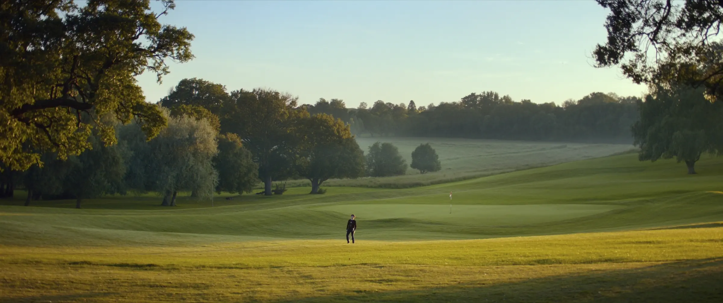 Low evening sunlight across the fairways of a parkland golf course